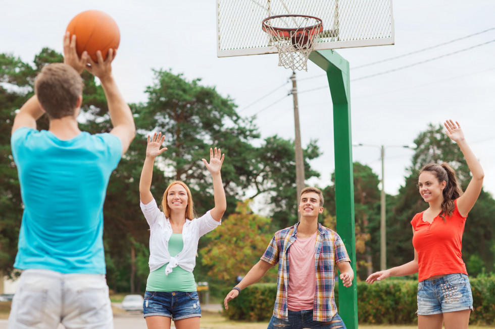 Mladostniki med igranjem košarke na zunanjem igrišču