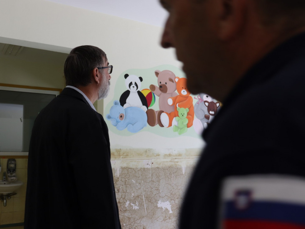 Minister Darjo Felda v ozadju na steni ilustracije živali.