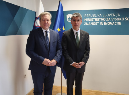 Minister Papič in dr. Shoji Asai pred zastavama Slovenije in EU v prostorih Ministrstva za visoko šolstvo, znanost in inovacije.