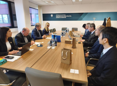 Srečanja dveh delegacij v sejni sobi ministrstva z zapiski, prenosniki in gradivi na mizi.
