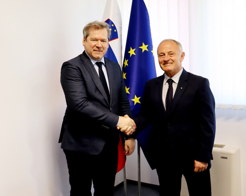 Rokovanje ministra in albanskega veleposlanika, v ozadju slovenska in evropska zastava.