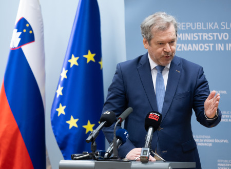 Minister dr. Papič za govorniškim odrom. V ozadju stojita slovenska in evropska zastava.