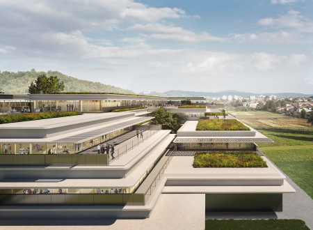 Pogled na terasasto zasnovano fakultete z zelenimi strehami in veliko steklenimi površinami, obdano s krajino.