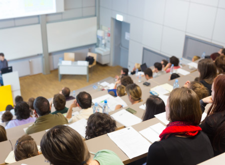 Študentke in študenti v predavalnici spremljajo predavanje profesorja.