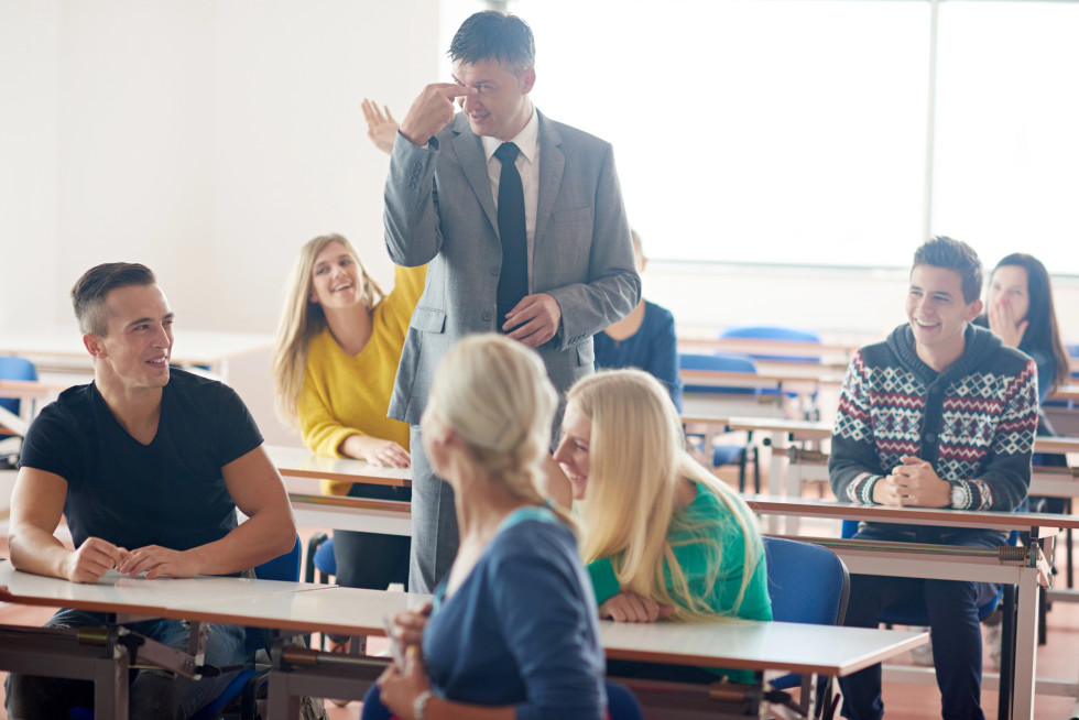 Profesor s študentkami in študenti v predavalnici.