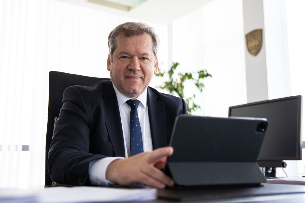 Dr. Papič za pisalno mizo, pred njim tablični računalnik.