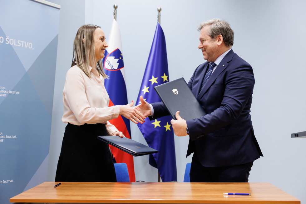 Rokovanje dr. Špele Miroševič in ministra Papiča po podpisu pogodbe. V ozadju slovenska in evropska zastava.