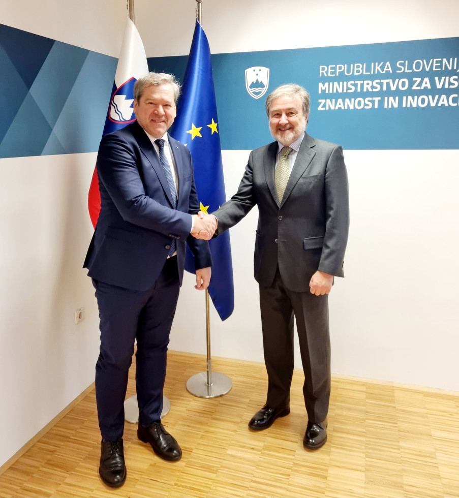 Minister Papič in španski veleposlanik Javier Herrero med rokovanjem, v ozadju slovenska in evropska zastava.