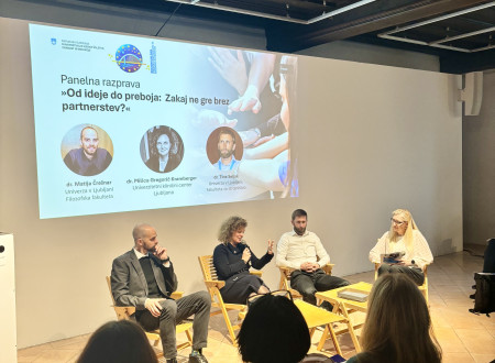 Druga panelna razprava s štirimi govorci, ki sedijo na odru pred projekcijskim zaslonom z naslovom dogodka.