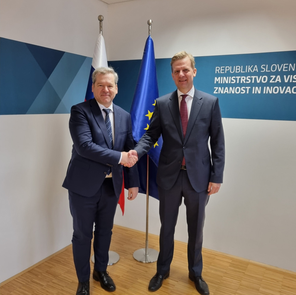 Minister in veleposlanik, v ozadju stojita slovenska in evropska zastava.
