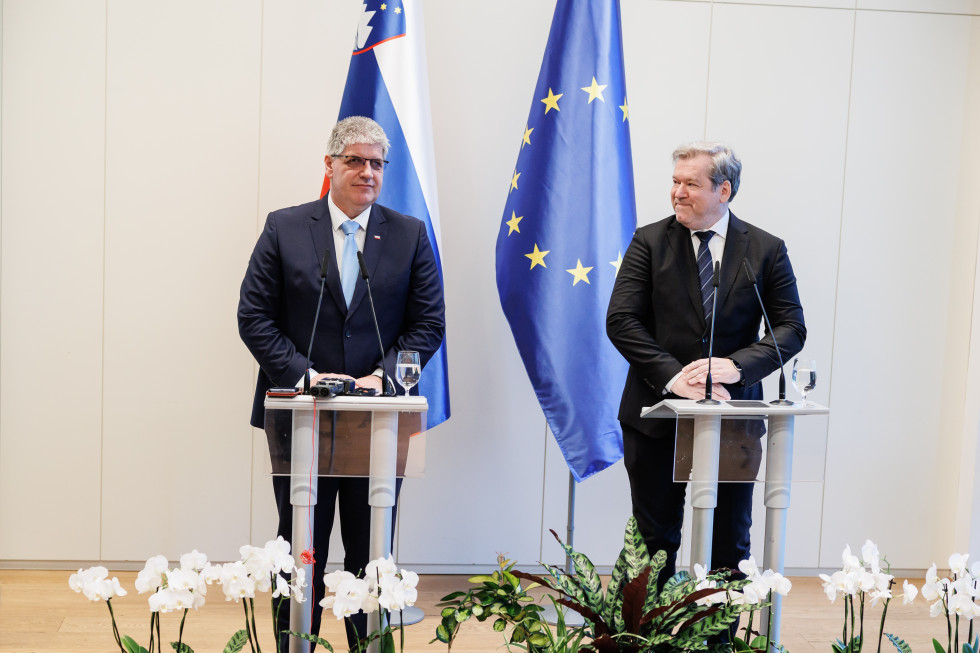 Ministra Poklukar in Papič za govorniškima pultoma na novinarski konferenci. V ozadju stojita slovenska in evropska zastava.