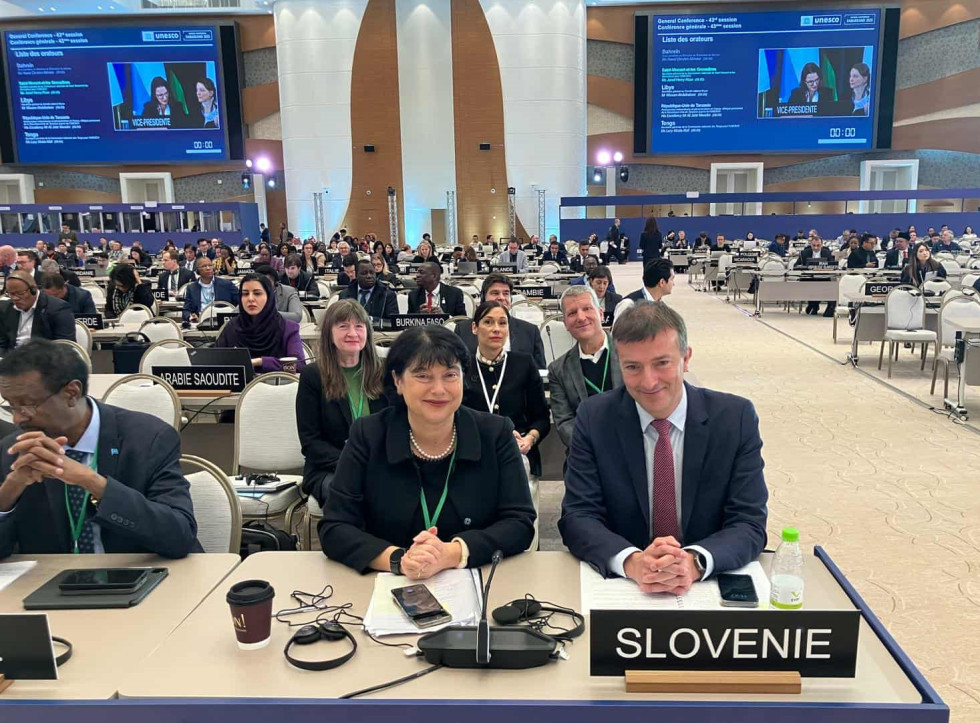 Slovenska delegacija sedi za mizo na zasedanju UNESCO med predstavniki drugih držav.