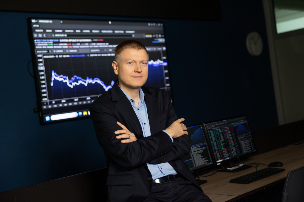 Prof. dr. Miroslav Verbič v poslovnem okolju sedi pred računalniškimi zasloni z grafi finančnih podatkov.