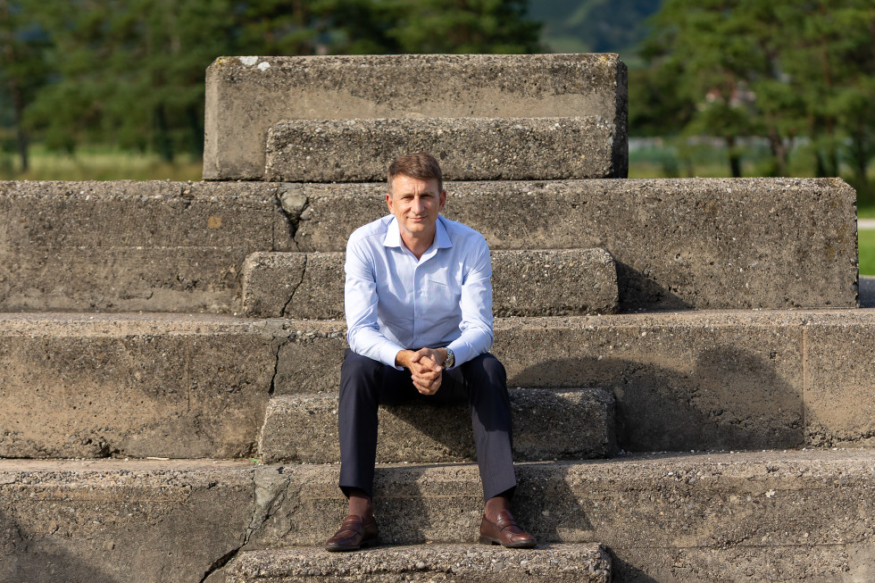 Prof. dr. Uroš Seljak, prejemnik priznanja ambasador znanosti Republike Slovenije, sedi na betonskih stopnicah na prostem.