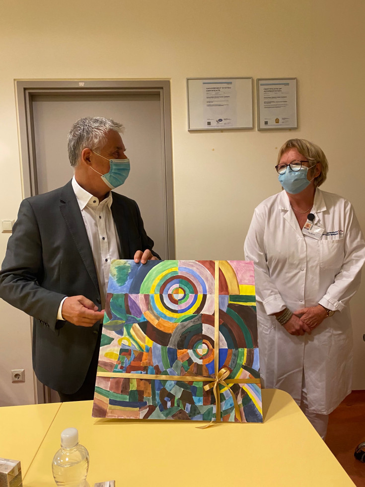 Tanja Bečan, vodja bolnišnične šole OŠ Ledina izroča ministru Tomažu Gantarju umetniško sliko.