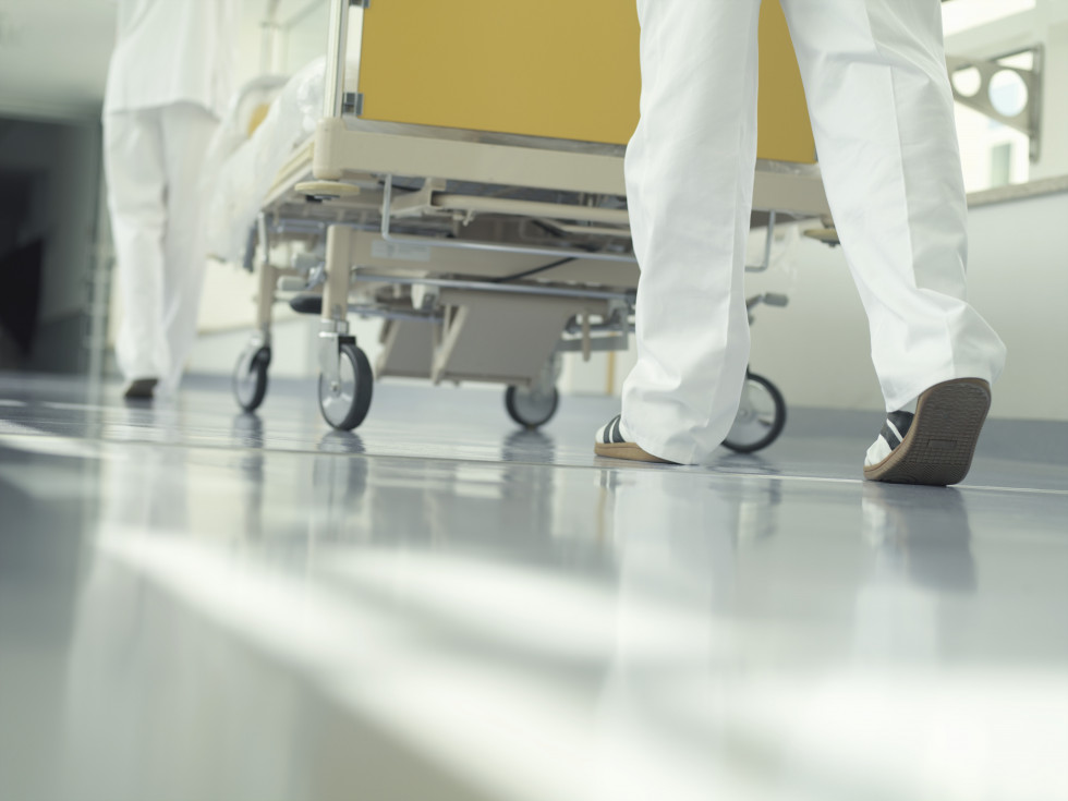 Pogled iz žabje perspektive na noge zdravstvenih delavcev ob bolniški postelji