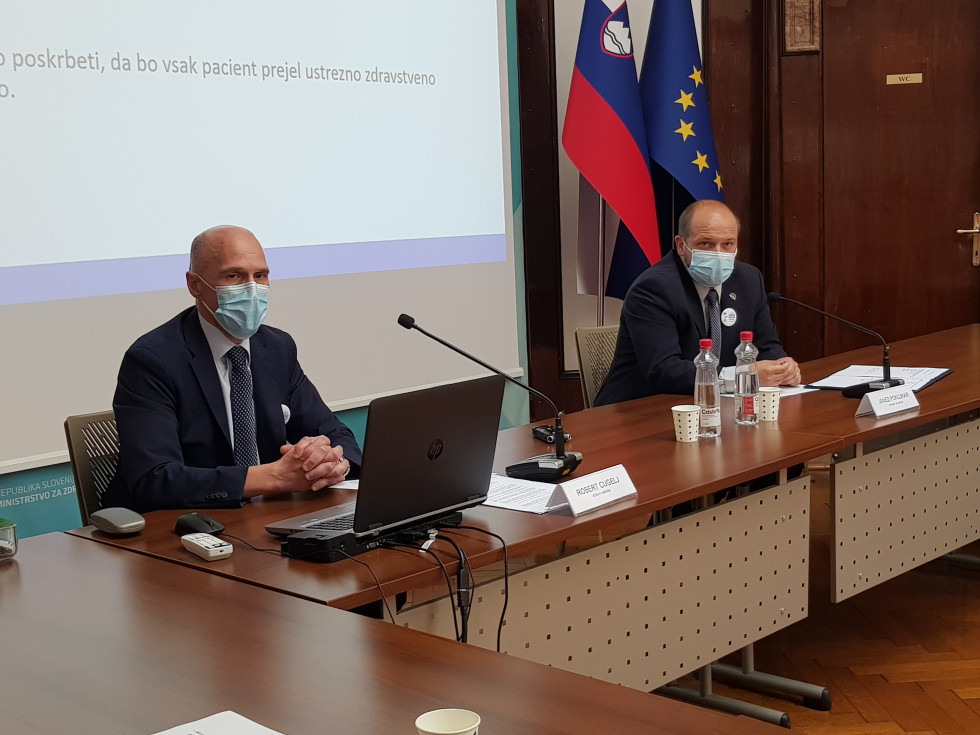 Državni sekretar in minister za konferenčno mizo, v ozadju zastavi Slovenije in EU.