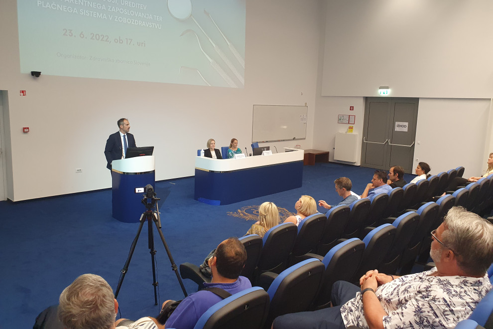 Državni sekretar Tadej Ostrc za govorniškim pultom in udeleženci tribune