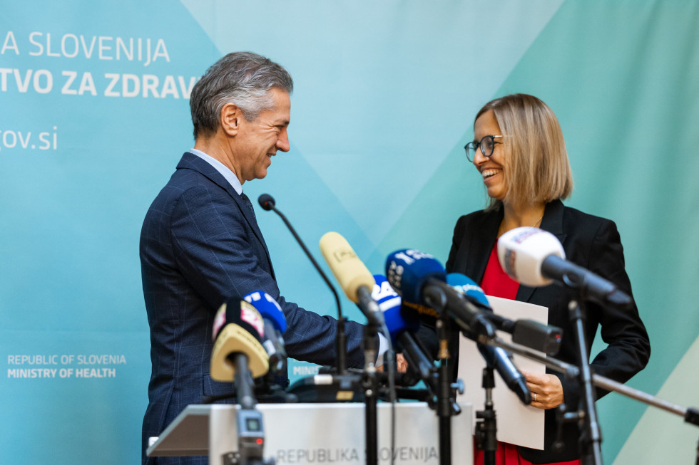 Premier v modri obleki čestita ministrici v rdeči majici in črnem suknjiču