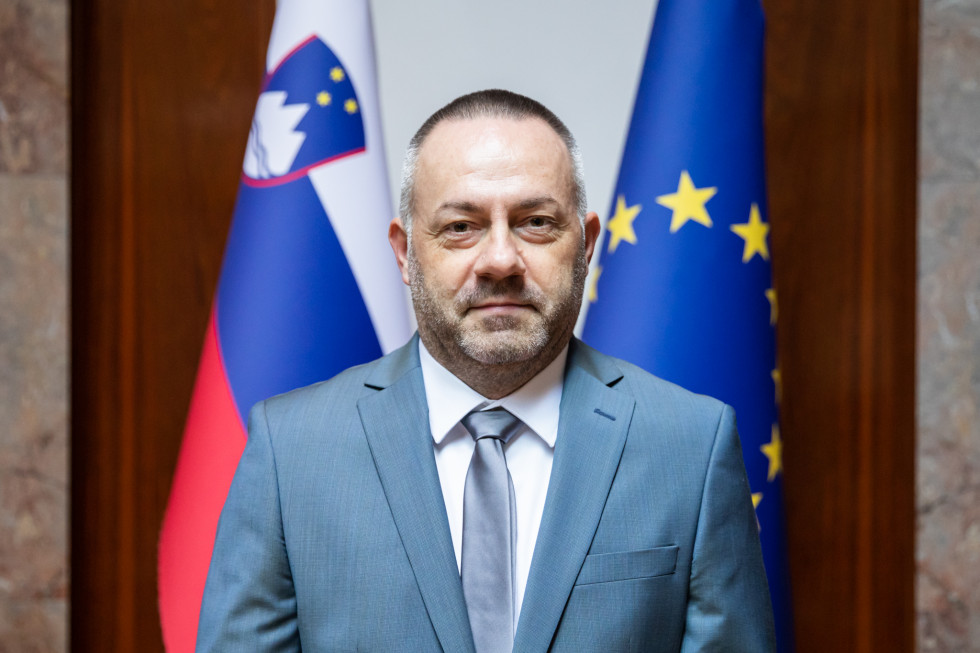 Minister za zdravje slikan pred slovensko in evropsko zastavo 