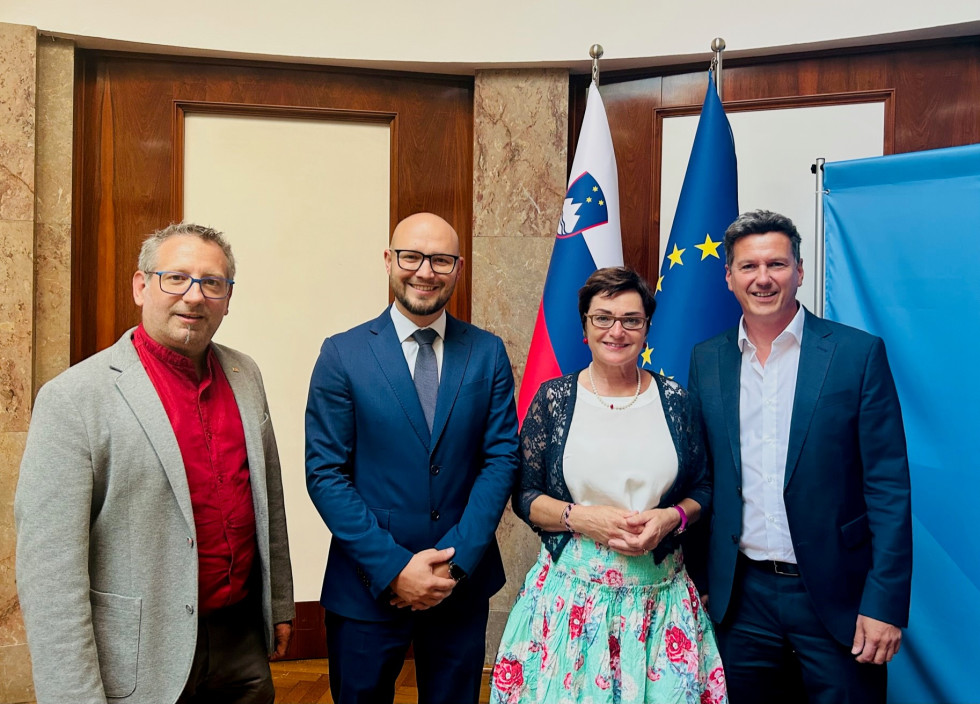 Denis Kordež, Beate Prettner, Daniel Fellner in Klausom Pabautzem stojijo pred slovensko in evropsko zastavo