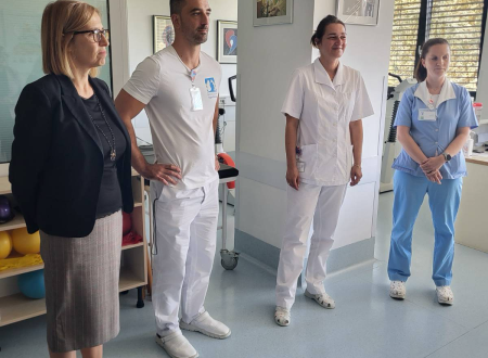 Ministrica stoji ob predstavnikih bolnišnice v sobi za rehabilitacijo 