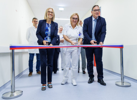 Tri osebe stojijo za trakom na hodniku in s škarjami režejo trak