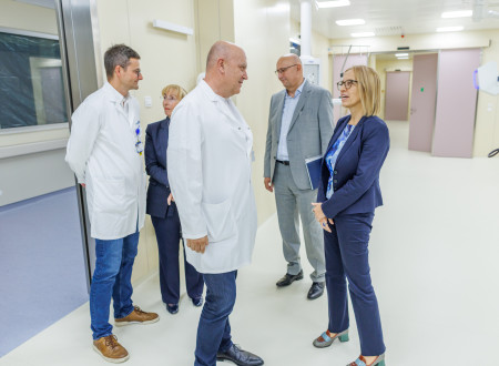 Ženska v temno modri obleki se pogovarja z zdravnikom v beli halji