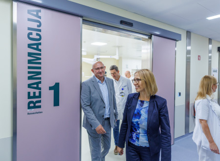 Ženska v temno modri obleki pred drsnimi vrati z napisom reanimacija 1