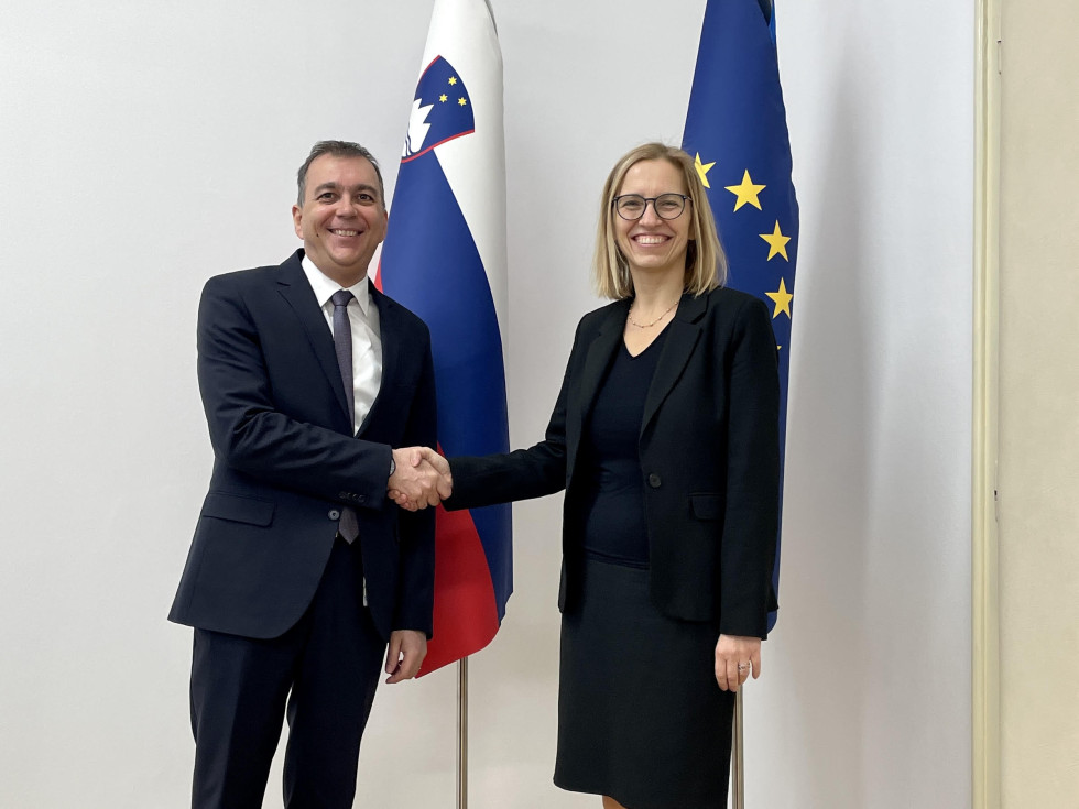 Ministrica za zdravje in generalni direktor ZZZS se stoje rokujeta pred slovensko in evropsko zastavo