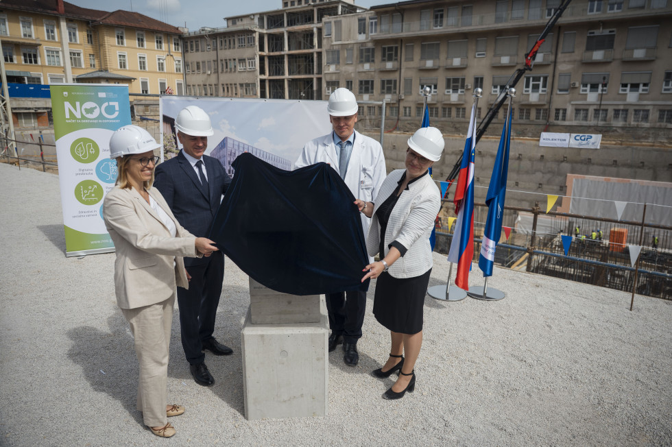 Ministrica za zdravje, predsednik vlade, vodja Predstavništva Evropske komisije v Sloveniji ter generalni direktor UKC Ljubljana dvigajo pregrinjalo, pod katerim je temeljni kamen