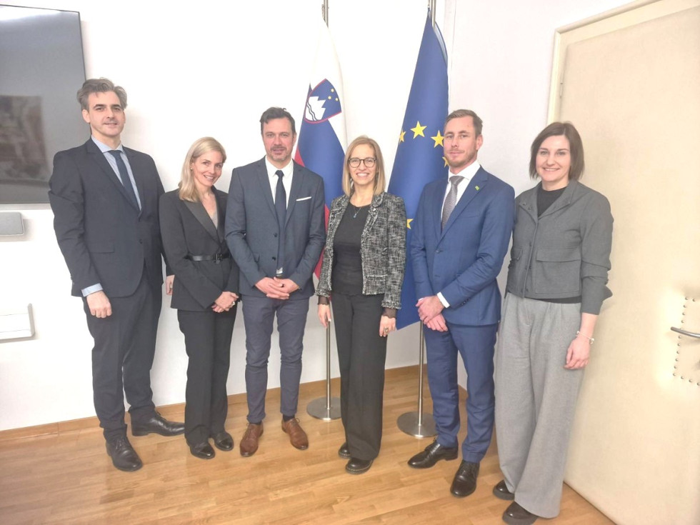 Ministrica stoji s predstavniki podjetja pred slovensko zastavo in zastavo EU