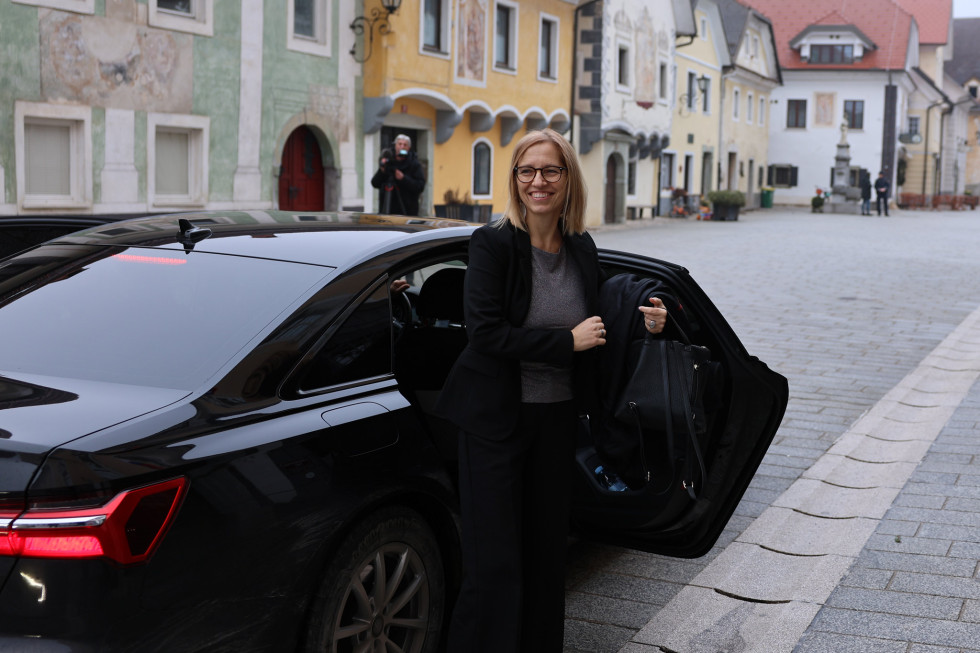 Ministrica izstopa iz črnega avtomobila.