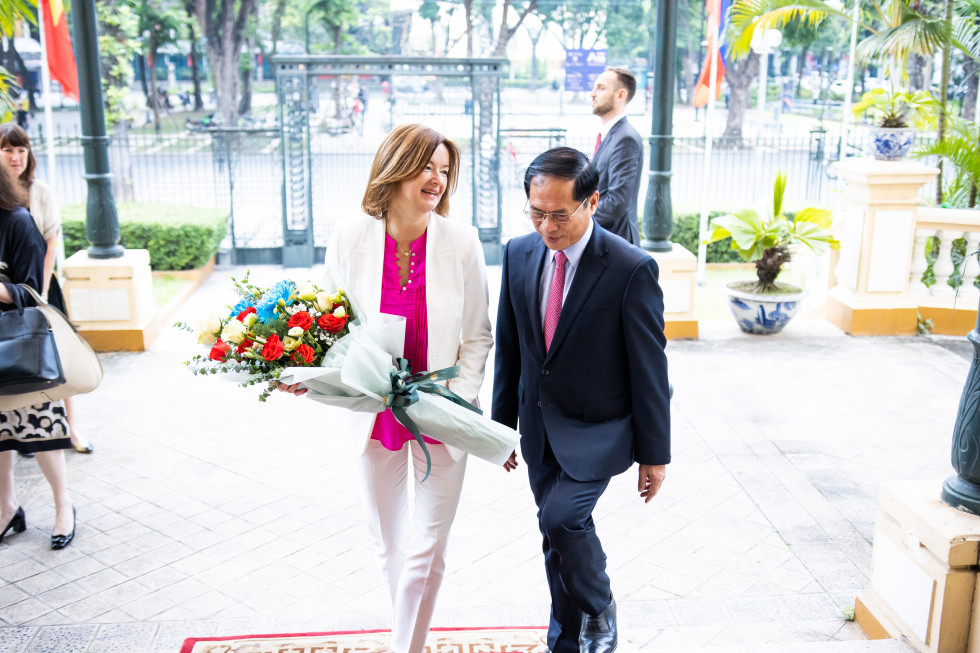 ministra hodita po rdeči preprogi, ministrica v rokah drži šopek rož