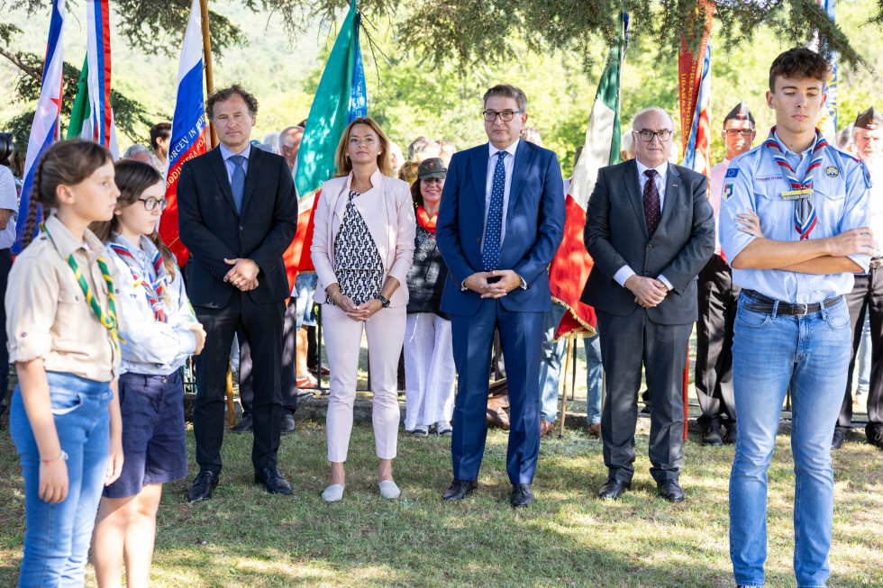 Ministrica Fajon in drugi udeleženci dogodka stojijo pred grobnico. 