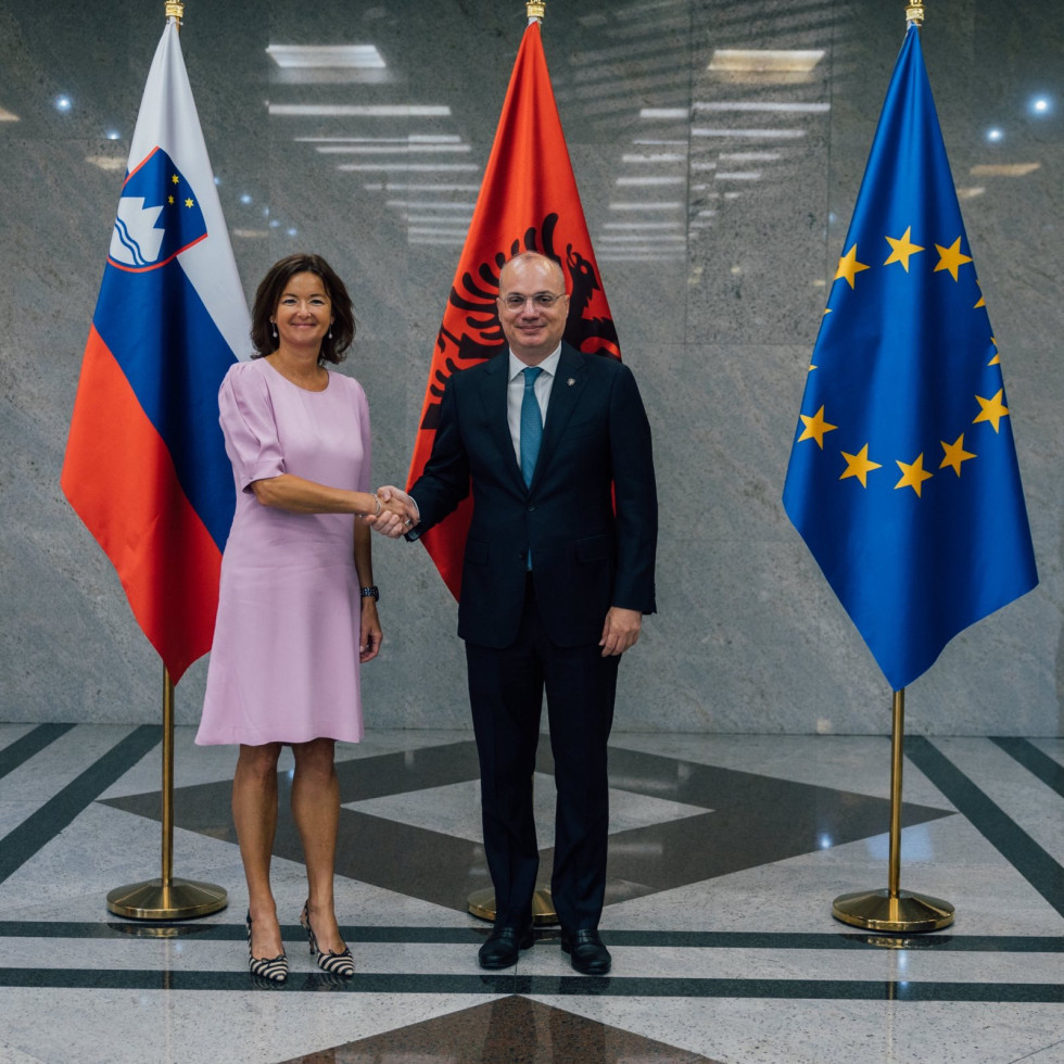 ministra se rokujeta pred zastavami