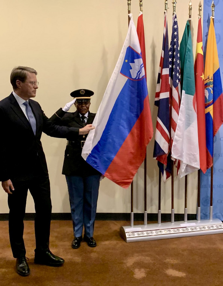 Državni sekretar Samul Žbogar med dvigom slovenske zastave, dotika se zastave