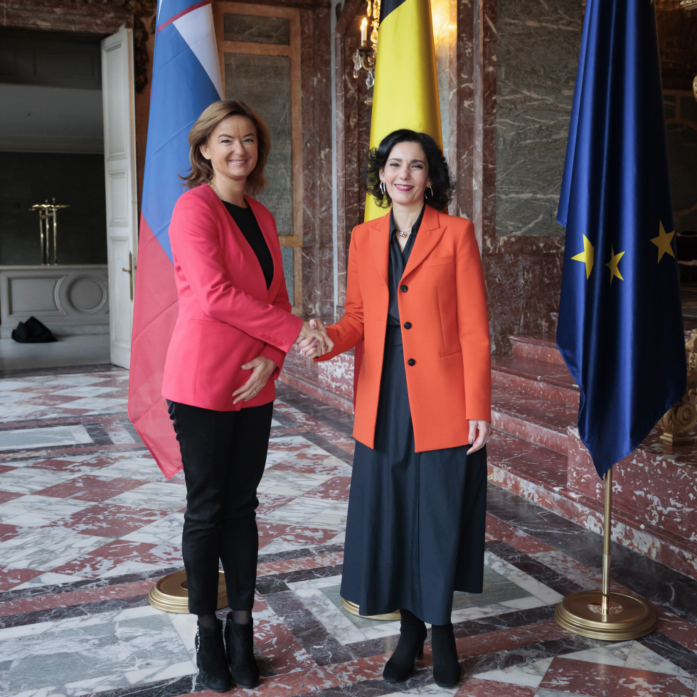 Minister Tanja Fajon shaking hands with Belgian Foreign Minister Hadja Lahbib, flags in the background