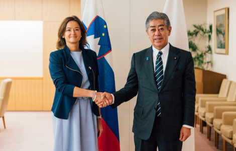 Gt4GL8FXEAAZ5QE (Ženska in moški se rokujeta pred zastavami.)