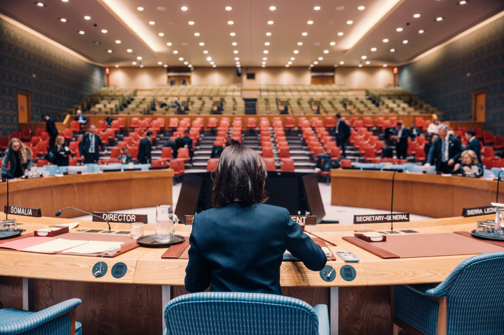 ministrica sedi na stolu predsedujoče, od zadaj videti celo dvorana