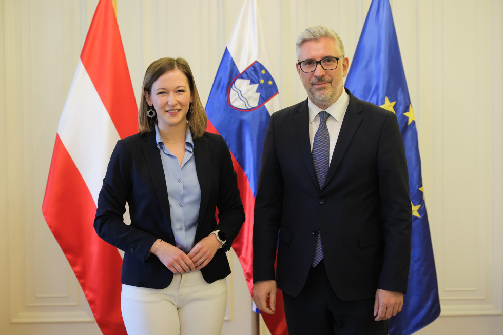 sogovornika stojita pred zastavami