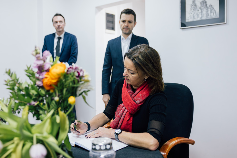 ministrica sedi, vpisuje se v knjigo, za njo makedonski minister stoji