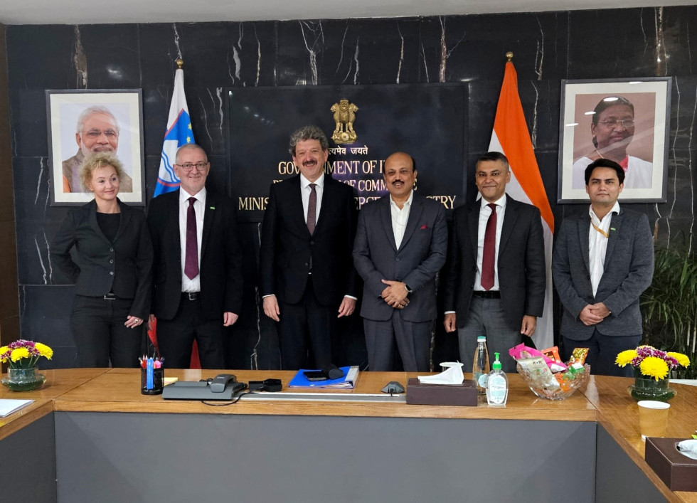 Skupina moških stoji pred zastavami