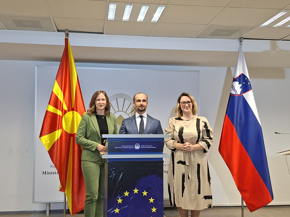 sogovornici z gositeljem stojita pred govornico