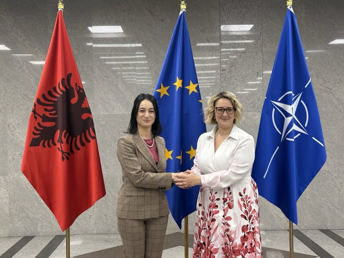 Dve ženski pred zastavami se držita za roko