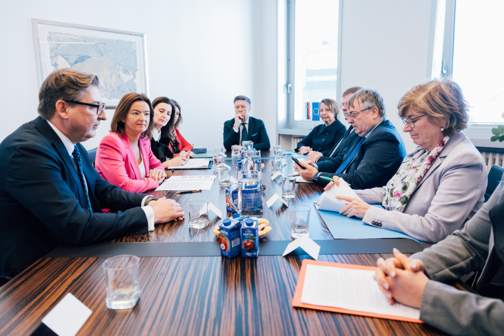 Ministrica s sodelavci sedi za mizo, ljudje nasproti nje