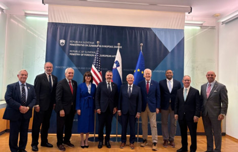 1214234 (Ten people dressed in formal business attire are posing in a large office in front of the flags of the United States, Slovenia, and the European Union)