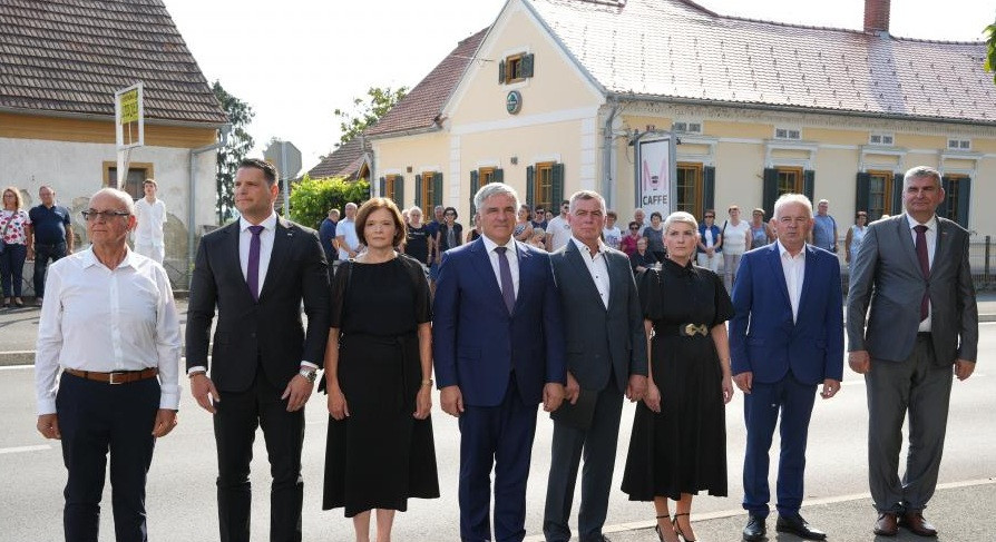 udeleženci stojijo eden poleg drugega, v ozadju hiša