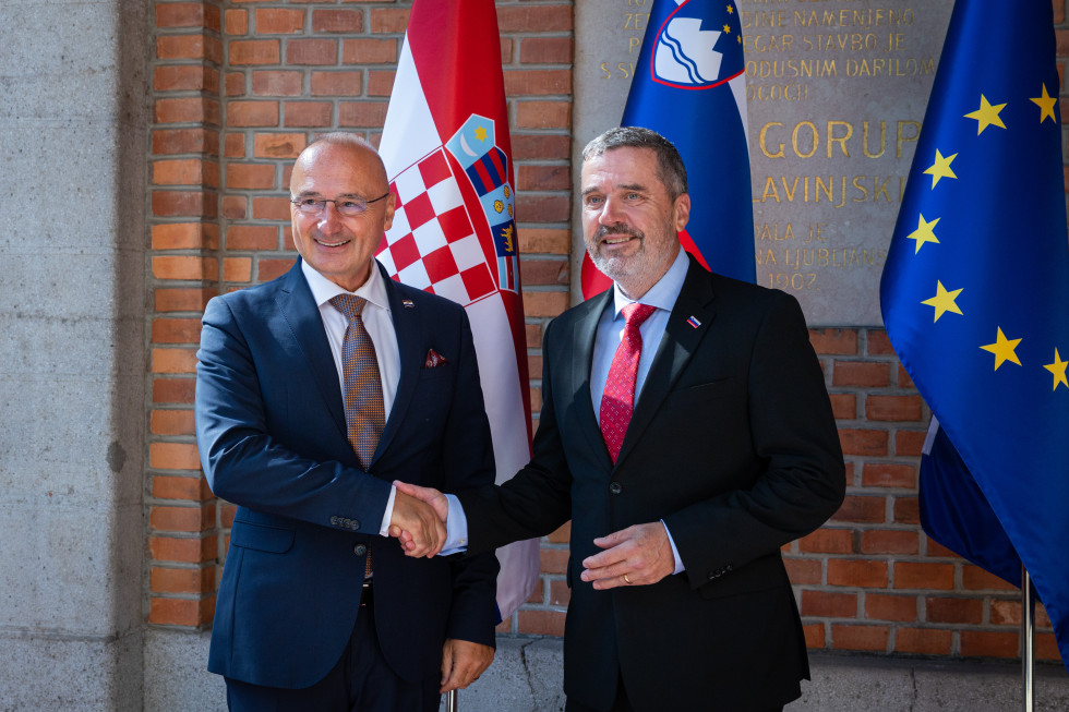 ministra se rokujeta pred zastavami