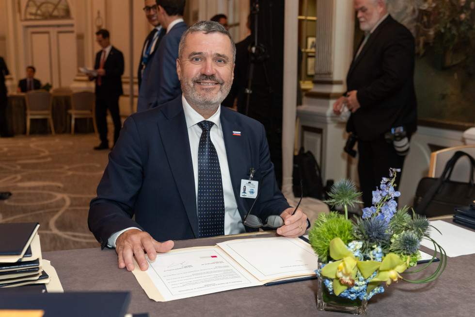 minister po podpisu, pred njim mapa z izjavo